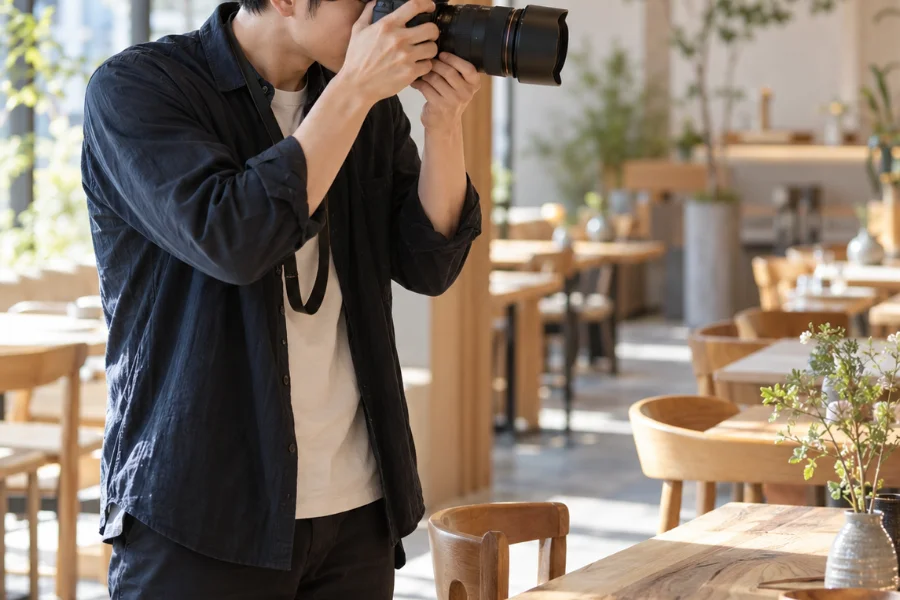 店内で一眼レフカメラを構えて撮影しているカメラマン